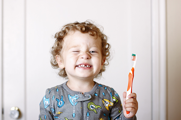 Toddler smiling while holding a toothbrush